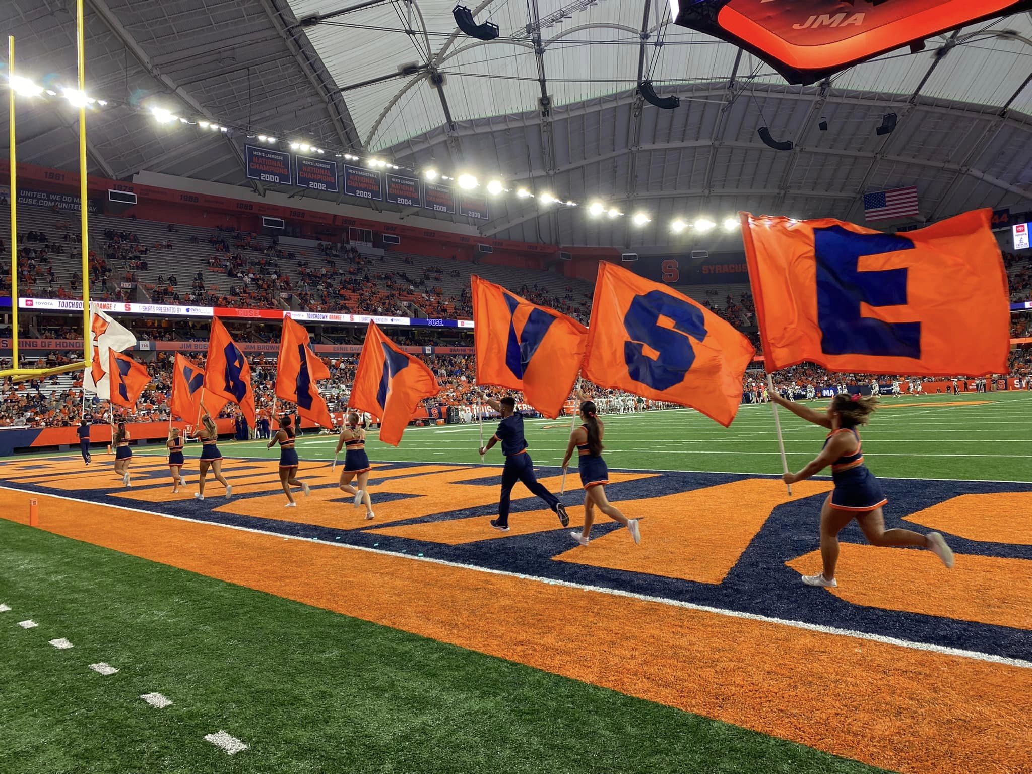 Cheerleaders on the JMA Wireless Dome field with Syracuse University flags