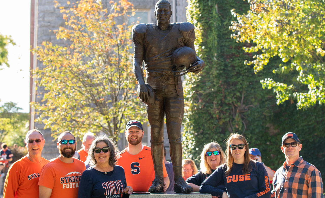Alumni pose with the statue of Ernie Davis