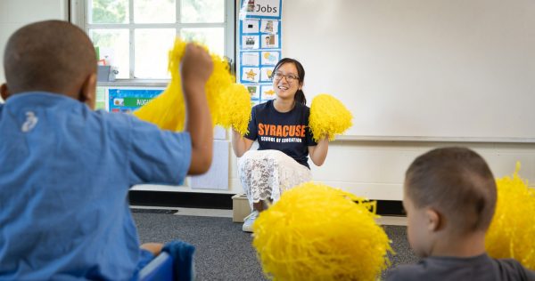 Emily Liu holding up pom pons with students