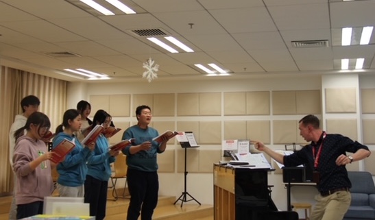 Graduate Evan Wichman leads a musical rehearsal with his students at the National Day School in Beijing