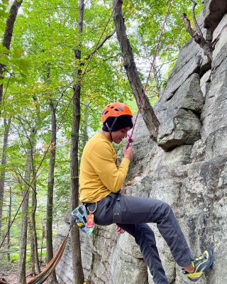 a person climbs a rock wall in nature with the assistance of a rope