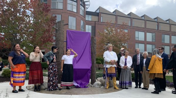 students, faculty, staff and members of the Onondaga Nation gather around the painting "Gayaneñhsä•ʔgo•nah" prior to the reveal on Shaw Quad