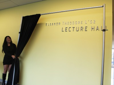 Student unveiling sign for Theodore Lecture Hall.