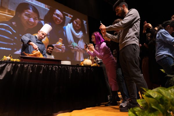 Chef carving turkey with students taking photo of him.