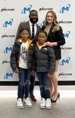 two adults and two children standing in front of a backdrop