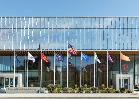 Outside of NVRC building on a sunny, blue sky day featuring the nine flag poles in front of the building with the various military flags