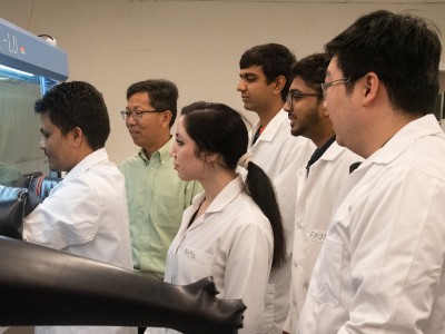 Professor and research team studying a solar cell.