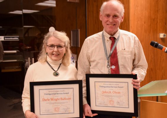 Darle Balfoort and John Olson hold up framed certificates of their recently received Libraries' Distinguished Service Award