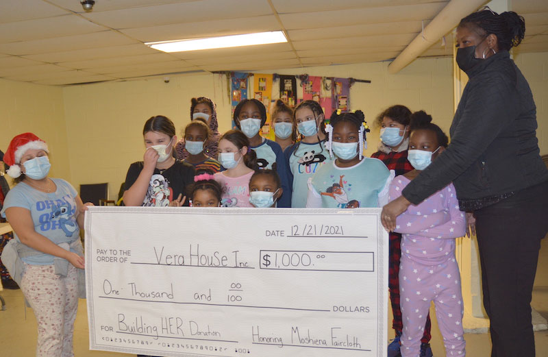 Moshiena Faircloth with children holding a large check to a local charity.