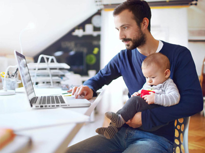 stock image of person working on a computer with a young child in their lap