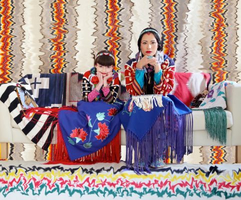 two people sitting on a couch with brightly colored fabrics