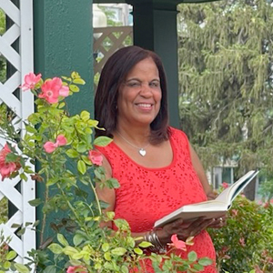 Woman smiling outdoors while holding a book.