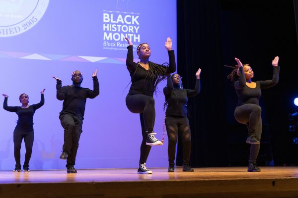Individuals lined up in two lines performing a step dance.