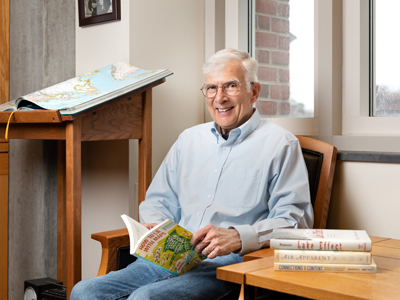 Man smiling in a chair while holding a book.