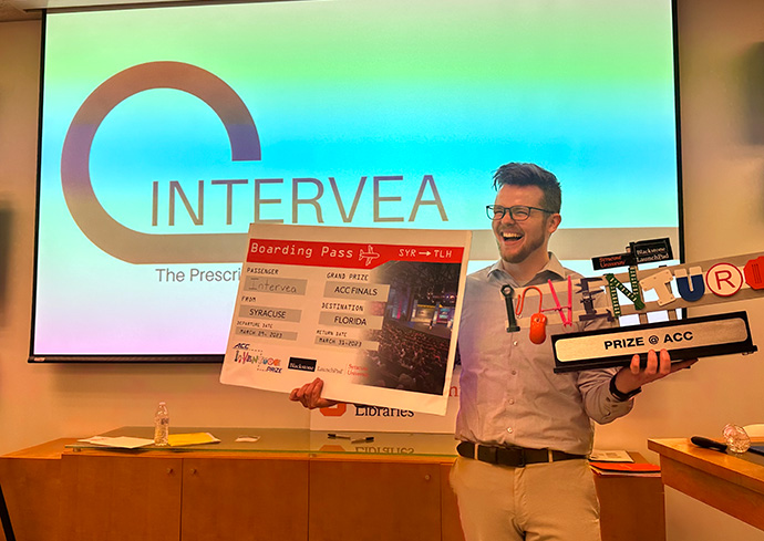 Individual standing in front of a presentation screen holding an award