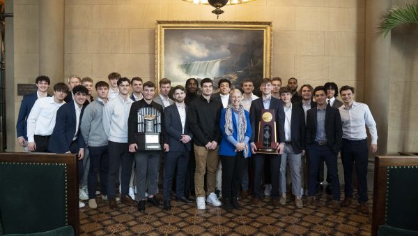 Soccer teams standing together holding NCAA trophy
