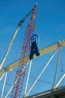 Letter "A" being installed by a crane to the crown truss on the exterior of the JMA wireless dome. 