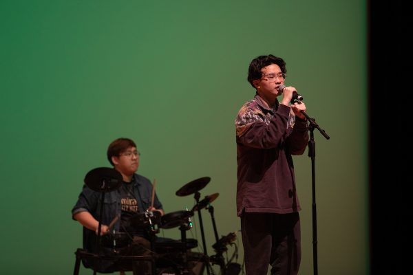 two students, one singing and one playing drums, during the Chinese Union Lunar New Year celebration
