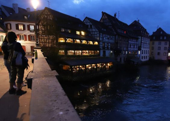 A view of several buildings and a river at dusk in Strasbourg, France