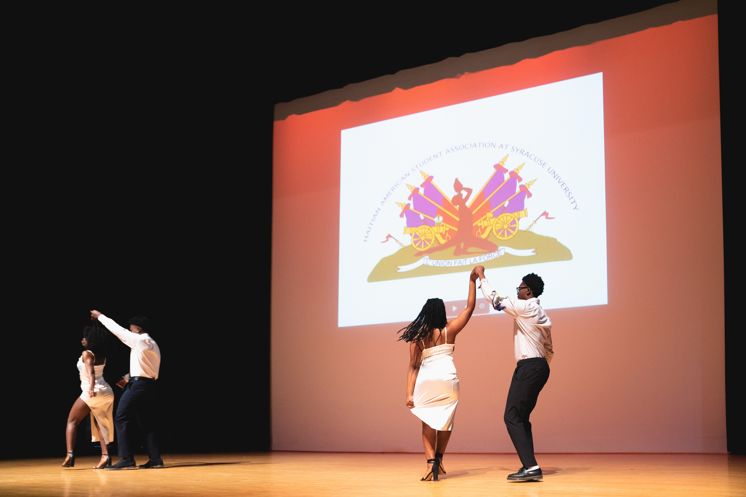 Two pairs of students dancing on stage at the Goldstein Auditorium. 
