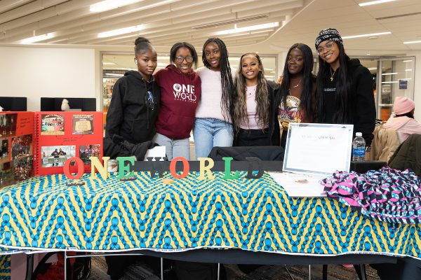students from the One World dance team pose together behind a table at the Black and Brown Informational Fair
