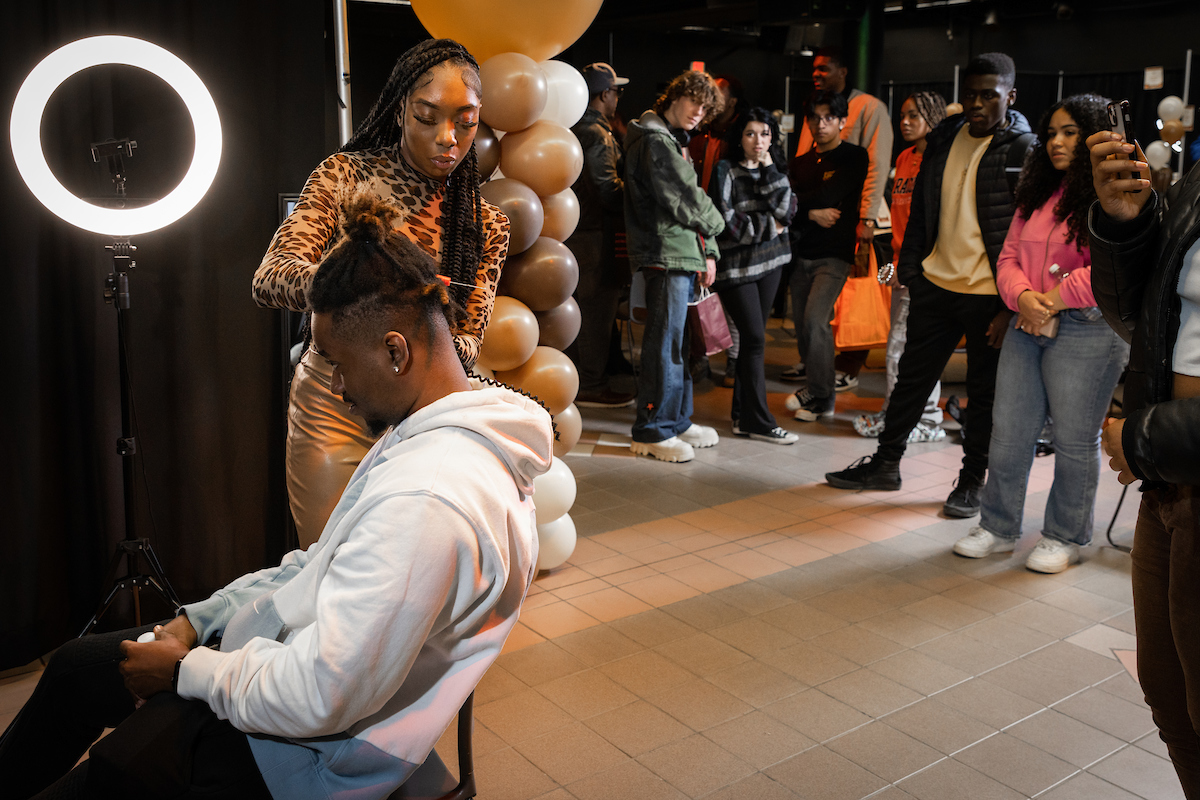 individual receives a haircut at the State of the Black Hair Experience event in February, while others watch nearby