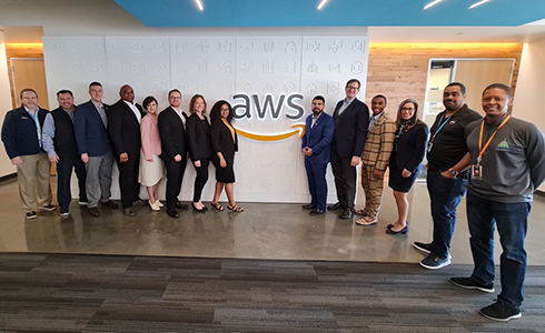 Group of individuals standing in front of AWS sign.