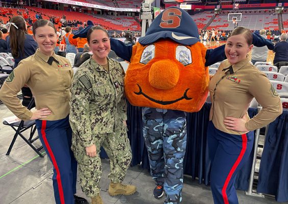 Three people in uniform standing with Otto at a basketball game