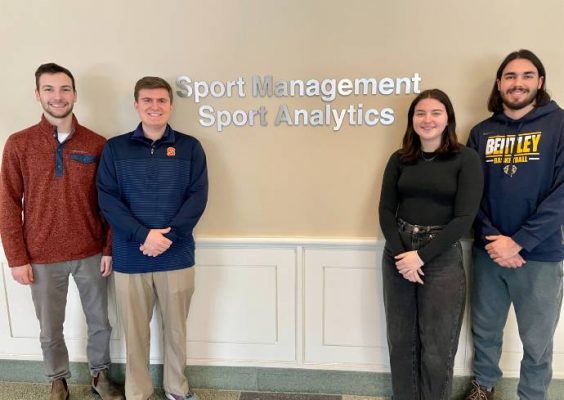 Four sport analytics students standing at Sport Management sign