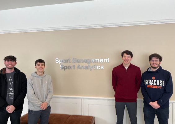 Four sport analytics students standing in front of Sport Management sign