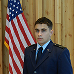 Man standing next to American flag in a military uniform.