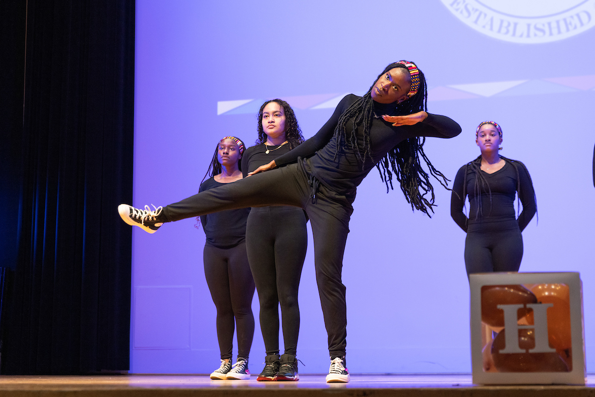 individuals dressed in black dance on a stage at the Black History Month Kickoff Celebration