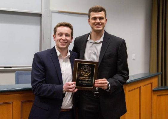 Two students holding plaque for finishing second at sport analytics competition
