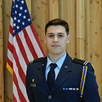 Man standing next to American flag in a military uniform.