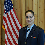 Woman standing next to American flag in a military uniform.