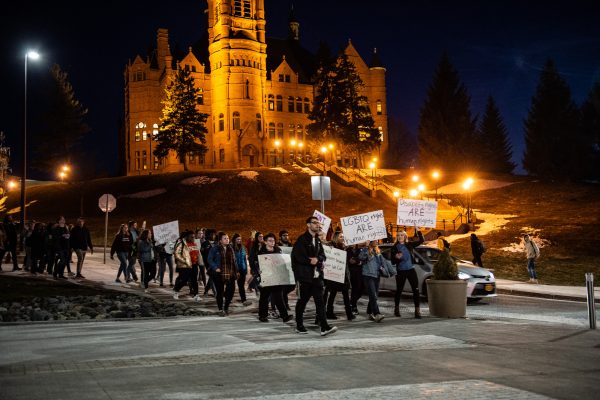 people marching on campus walkway holding signs