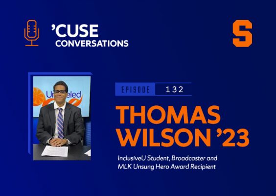 A man smiling at a news anchor desk with the Cuse Conversations Podcast logo and block Syracuse University S logo in the backdrop.