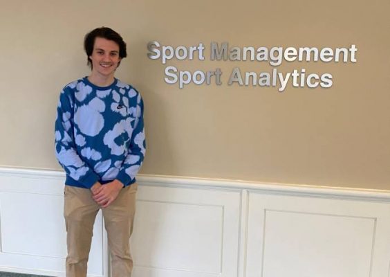Student standing in front of Falk Sport Management sign