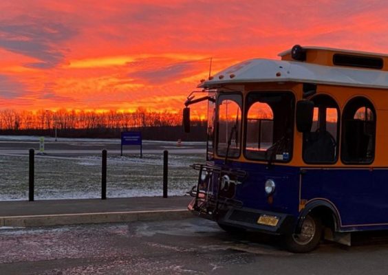 the front of a ’Cuse Trolley parked o the side of the road in front of a vivid sunset