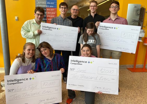Teams of students pose for a picture with a winning check during the Intelligence++ Design competition.