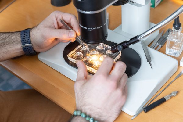 hands holding a sample under a biology lab microscope