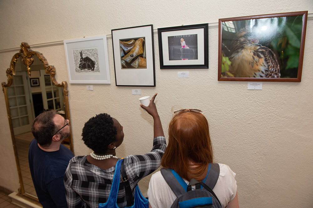 three people view artwork at the 2018 On My Own Time awards reception