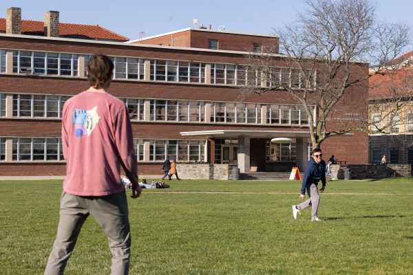 Students throwing a frisbee on the quad on a sunny day.