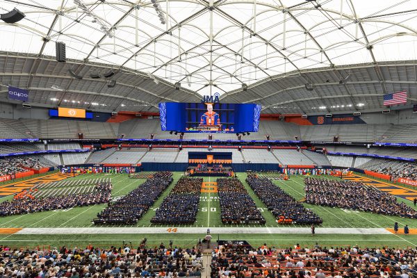 a wide view of the inside of the JMA Wireless Dome, with Chancellor Kent Syverud speaking on the videoboard, at Commencement 2023