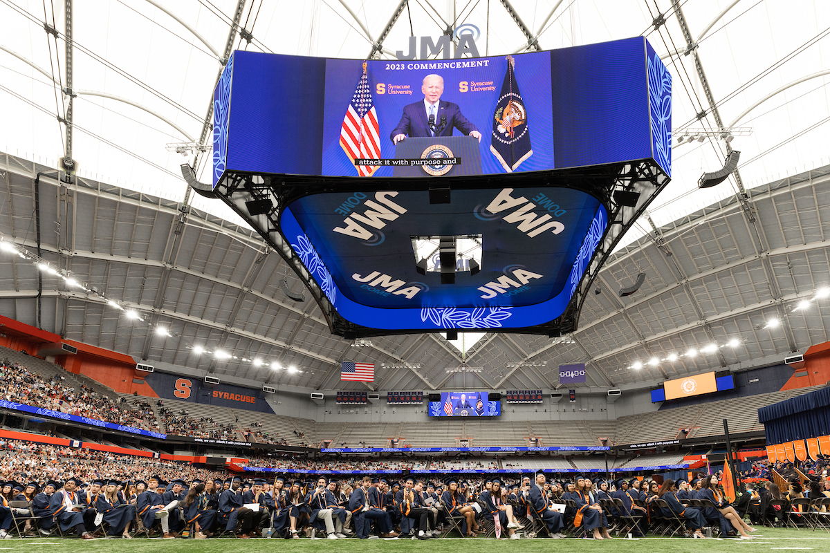 President Joe Biden delivers a virtual address to graduates on the videoboards in the JMA Wireless Dome at Commencement 2023