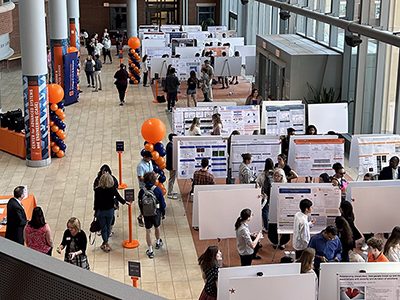 Overview of an atrium filled with poster presentations set up and people presenting to those in attendance