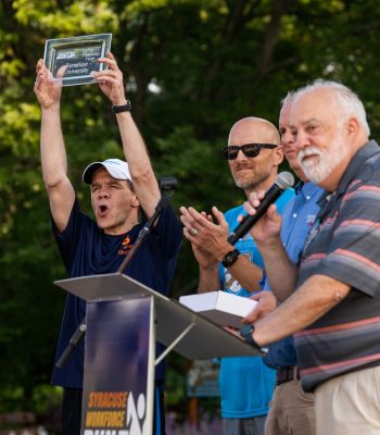 Dean Cole Smith holds up an award for Largest Company Team at the 2022 Syracuse WorkForce Run