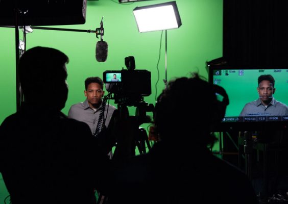 Student in front of green screen being filmed