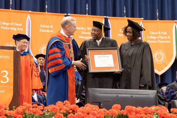 Deryk and Cynthia Banks accept a posthumous honorary degree from Chancellor Kent Syverud on behalf of their daughter, Cerri A. Banks ’00, G’04, G’06