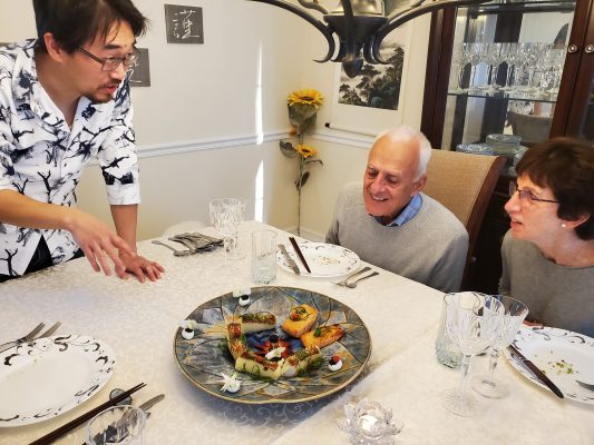 Three people sit around a dining room table learning how a professor incorporates his research into a culinary dish.